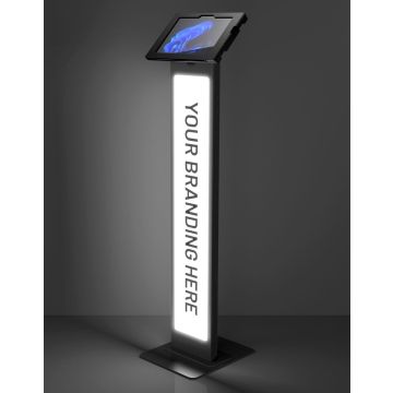 Studiofoto van de zwarte Compulocks BrandMe Lumina Apex vloerstandaard voor Microsoft Surface Go 4, schuin van voren met verlicht reclamepaneel.