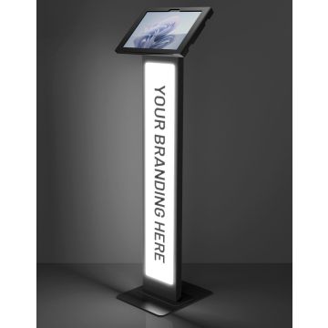 Studiofoto van de zwarte Compulocks BrandMe Lumina Apex vloerstandaard met Microsoft Surface Pro 11, voorzien van een verlicht brandingpaneel.